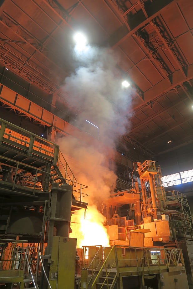 Dégagement calorifique d'un four d'aciérie en pleine opération, montrant des flammes et des gaz chauds.