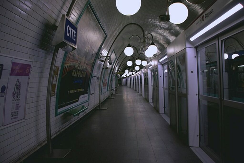 Station de métro parisienne avec des carreaux bleus traditionnels et des panneaux indiquant la direction.